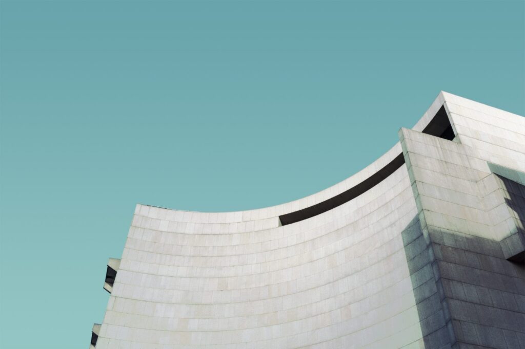 The sweeping concave roofline of a pale stone building against a teal sky.