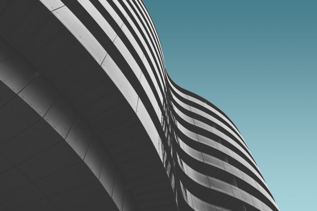 Curved balcony bands running across a building facade against a teal sky.